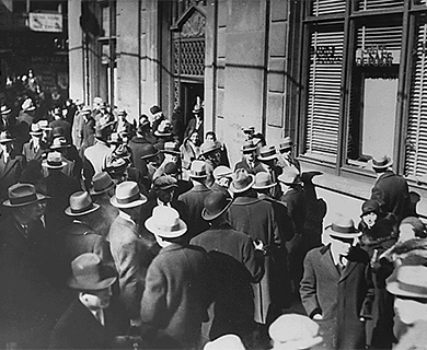 This image is a photograph of people lining up outside of a bank in hopes of withdrawing their funds during the Great Depression.