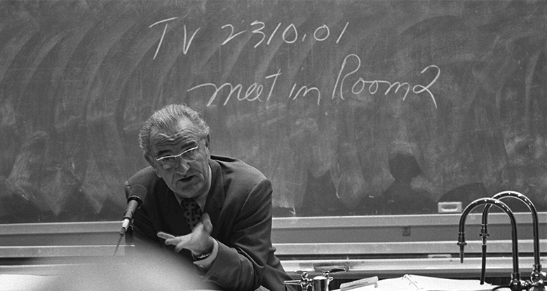 This is a photograph of Lyndon B. Johnson in front of a chalkboard.