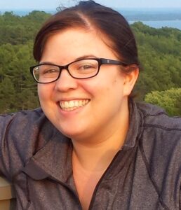 A smiling woman with brown hair and glasses